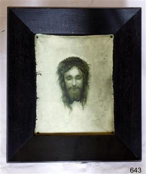 Portrait of Christ-like person, printed in dark colour on light canvas-like paper, framed in a wide wooden dark frame.