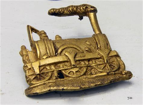 Gold coloured metal badge of a steam train engine