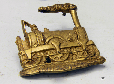 Gold coloured metal badge of a steam train engine