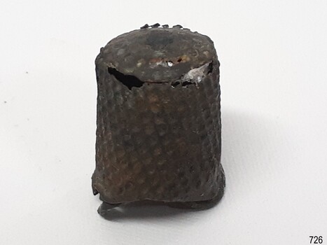 Metal flat-top dome, hollow inside. Surface is textured with dimples. It has some holes.