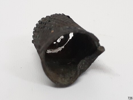 Thimble is buckled, base rolled and split, top coming away from sides, holes where there were dimples