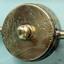 Metal is pitted. Brass disc with sphere protruding from the centre and cylindrical handles on opposide sides