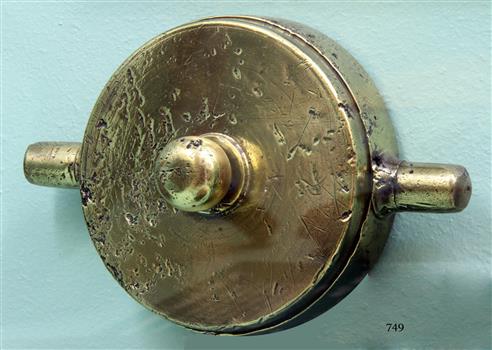 Metal is pitted. Brass disc with sphere protruding from the centre and cylindrical handles on opposide sides