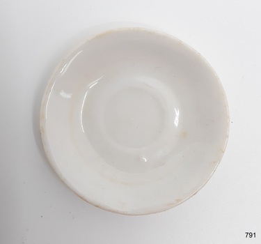 Saucer has a lump under the glaze and a round brown stain. 