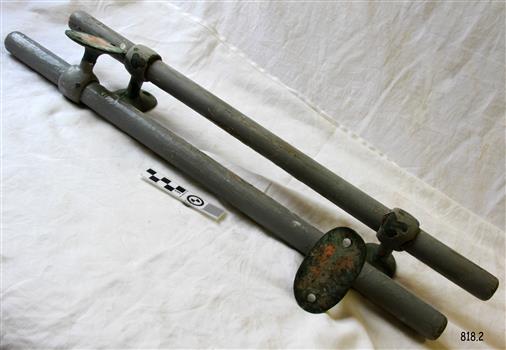 Grey painted wooded rods each with metal brackets at their ends