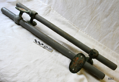 Grey painted wooded rods each with metal brackets at their ends