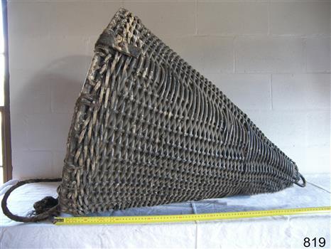 Woven cane cone, painted black, with a vertical metal rod through the centre.