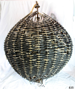 Woven cane ball, painted black, with vertical metal rod through the centre.