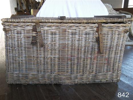 Front of basket with two leather straps and buckles for fastening the woven fitted lid on top. The wooden reinforcing lengths on the lid are also visible.
