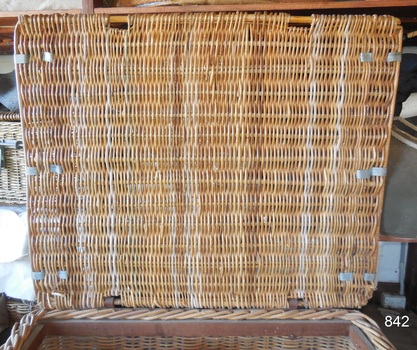 The underside of the lid is neatly finished. Here the metal reinforcing straps can be seen, three on each of the short sides of the lid. The strong timber frame can be seen around the top edges of the basket.