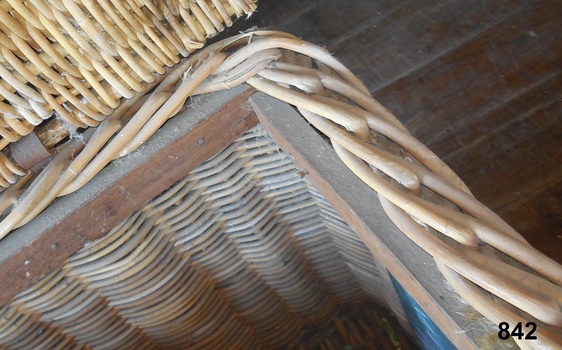This close up photo shows the wicker attached to the wooden frame. 