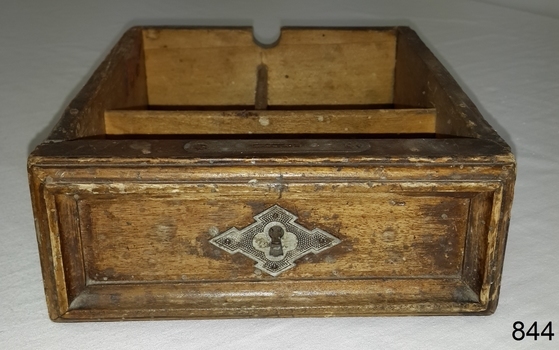 Drawer has decorative wooden trip and fancy metal plate around key hole