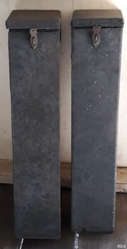 Two tall black rocket head toting boxes with lids closed, standing upright.