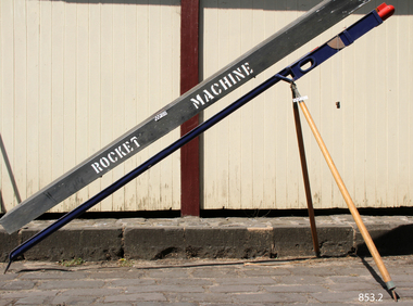 Rocket launcher machine in firing position, with rocket inserted. Box for launcher is positioned above it.