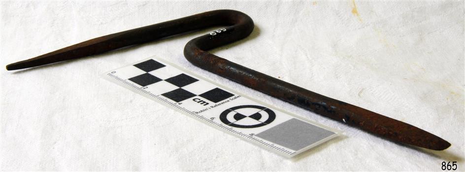 Metal rod a pointy end and a flat end, bent into a goose-neck at the centre