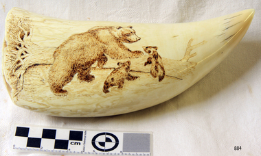 Carved grizzly bear with two cubs in front of a fallen tree