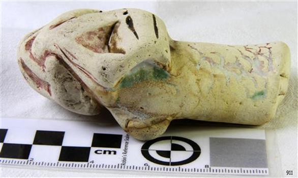Ceramic piece has been shaped and has remnants of burgundy, green and yellow glaze