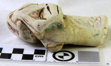 Ceramic piece has been shaped and has remnants of burgundy, green and yellow glaze
