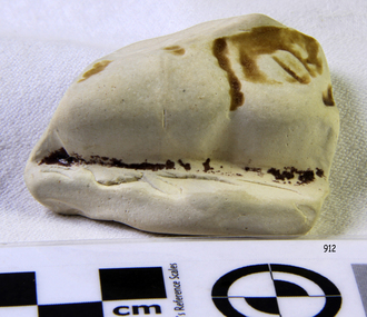 Piece has been shaped and has brown glaze remnants