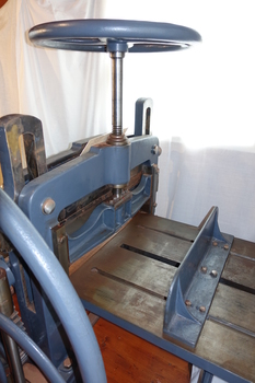 The top wheel is threaded into the central bridge over the bed. The rear vertical plate is adjustable.