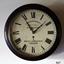 Round timber encased clock has Roman numerals, two hands, text and a key hold.
