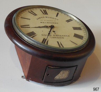 Clock's case has curved base wit hinged access door. Door has a keyhole and an attached label