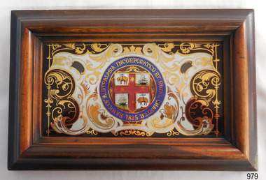 Insignia painted onto glass and mounted in wooden frame