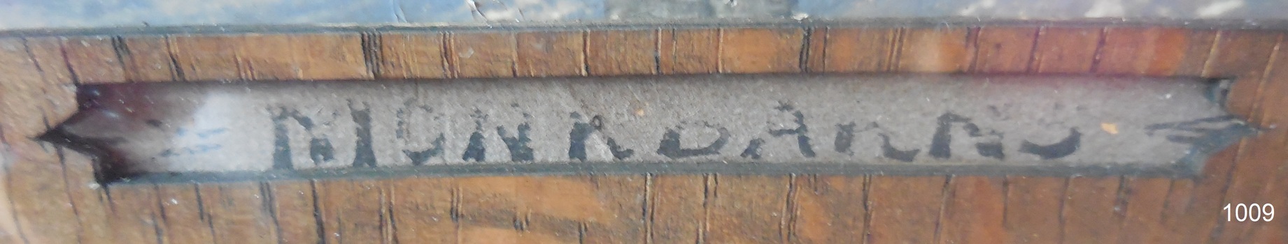 Inscription written in pen within carved out rectangle in matte