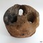 Round timber block with three holes. There is a nail in the centre.