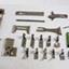 The set of accessories is laid out on the table. Most of the parts are a variety of feet to use with the machine for different effects and purposes. There are also some metal tools, a marking crayon and other parts.