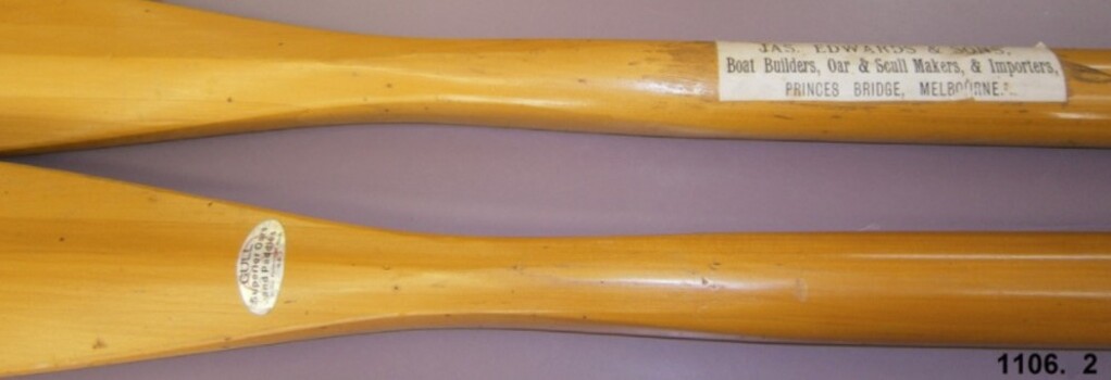 Both oars have a label adhered to them, one oval, one rectangular