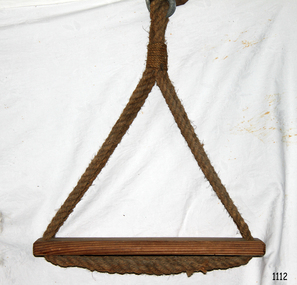 Wooden plank has ends of rope loops threaded through holes in seat and spliced together under seat.