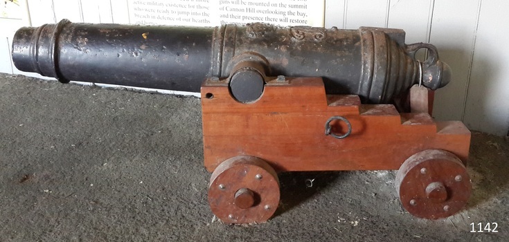 Black metal deck cannon or carronade on wooden carriage with wheels