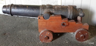 Black metal deck cannon or carronade on wooden carriage with wheels