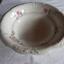 White porcelain bowl has fink and green floral motifs.
