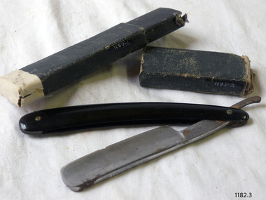 Raxor folds in half. Its handle is shiny black material. Black card box has slide-off lid. 