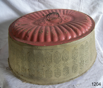 Oval metal food cover with handle. Painted green on the perforated side and pink on the top.