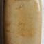 Surface of the base below the dark glaze of the shoulders looks rough and has different colourings, vrom cream to red-brown to holey coloured. The pencilled inscription is visible but indecypherable in places. 