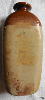 Surface of the base below the dark glaze of the shoulders looks rough and has different colourings, vrom cream to red-brown to holey coloured. The pencilled inscription is visible but indecypherable in places. 