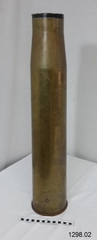 Upright shell has shiny brass outer surface with dark markings