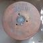 Round base facing viewer, showing inscriptions, indented circle in centre and three holes around it