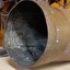 Shell laying on bench, view of edge and inside of mouth, wihci is dark metal with white chalky marks