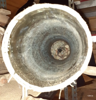 View from mouth to base, with white chalky rings on the inside metal and a hole in the base