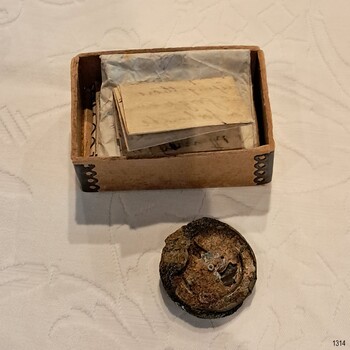 Cardboard box has metal reinforced corners and contains documents