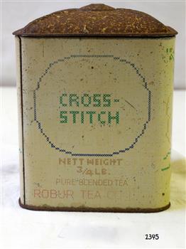  A square upright tin with lid, previously containing ¾ lb of tea. The front shows the words 'Cross-Stitch' and also 'Robur Tea Company' and 'Pure Blended Tea' .