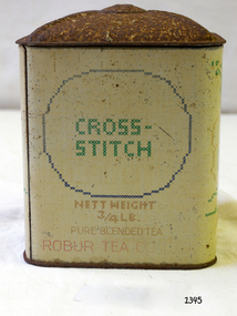  A square upright tin with lid, previously containing ¾ lb of tea. The front shows the words 'Cross-Stitch' and also 'Robur Tea Company' and 'Pure Blended Tea' .