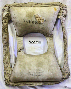 Inscriptions on front and back pockets, hole exposes kapok filling
