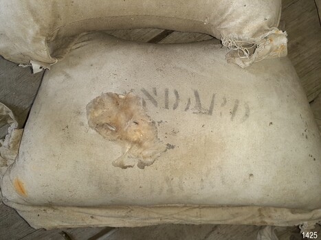 Filling showing through hole in compartment. Inscription stencilled onto canvas.