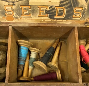 Compartment contains several cones of cotton thread.