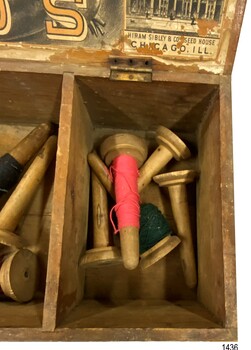 Compartment has several wooden cones of cotton thread